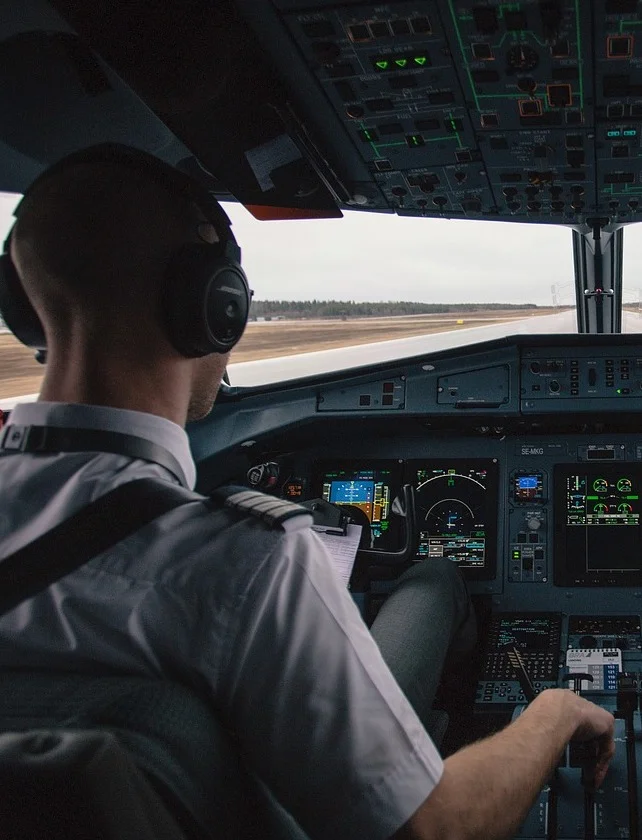 Pilot w kokpicie samolotu, ilustruje komunikację i współpracę zespołu w szkoleniach biznesowych inspirowanych lotnictwem